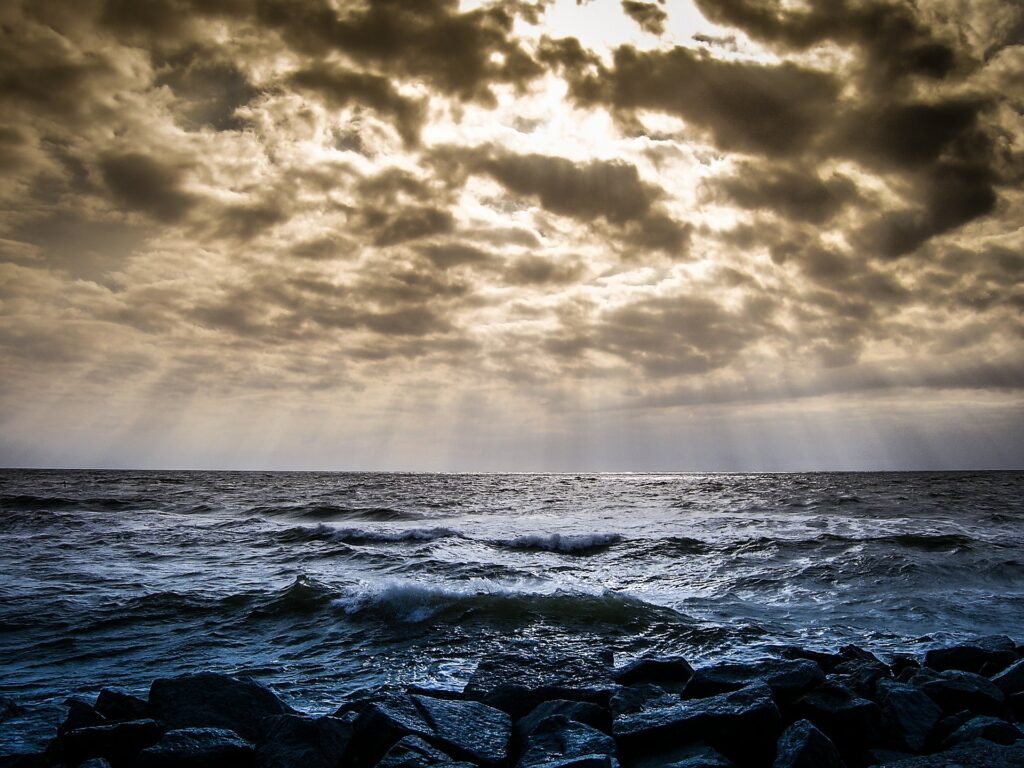Waves at the sea and sunbeams shining through the clouds